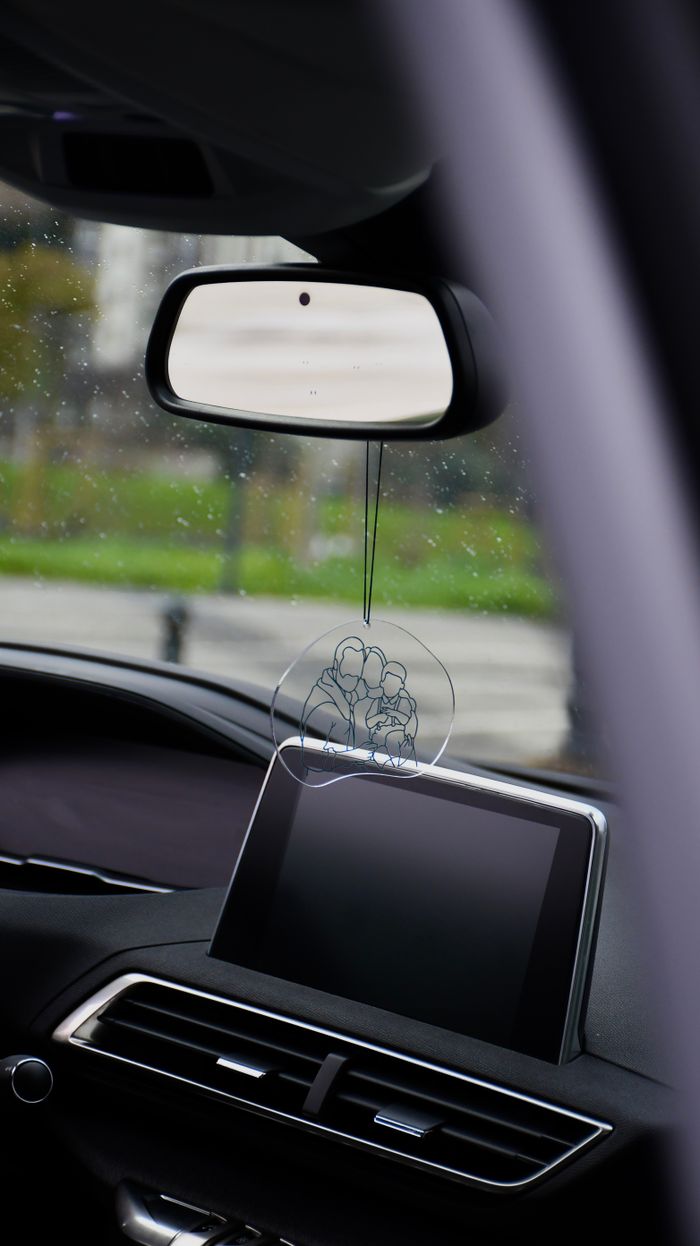 View from inside a car showing rearview mirror and dashboard with an air freshener.